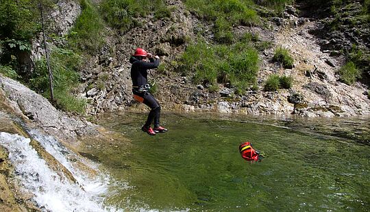 Teilnehmender springt bei einer Canyoning-Tour in ein natürliches Wasserbecken