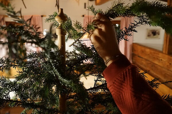 Person steckt einen Weihnachtsbaum aus Nadelbaumzweigen zusammen