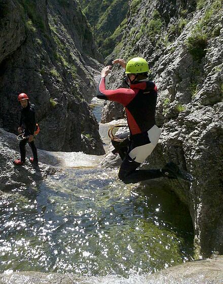 Person springt beim Canyoning bei Lenggries in Bayern in eine Gumpe
