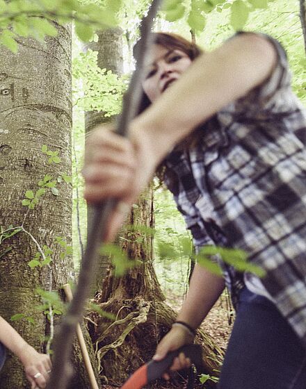 Zwei Personen beim Herausschneiden kleiner Äste im Wald 