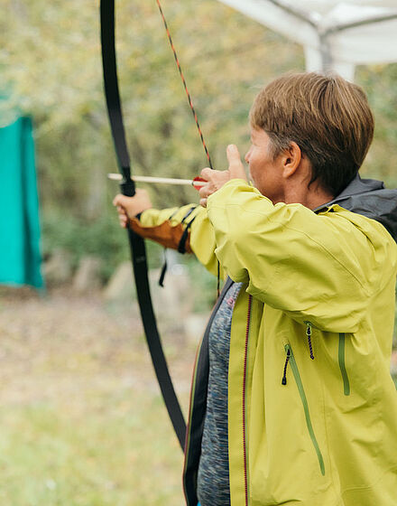 Person konzentriert sich beim Bogenschießen während eines Montevia-Teamevents