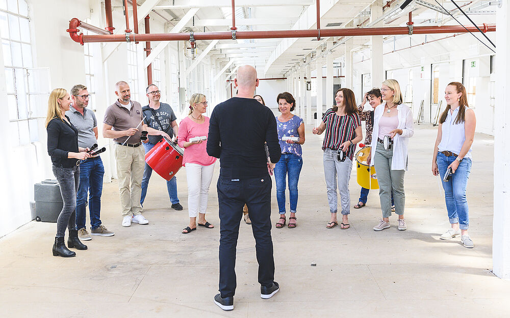Trommeltrainer leitet Workshop vor einer Gruppe mit verschiedenen Percussion-Instrumenten
