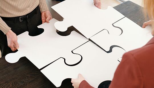 Team setzt überdimensionale Puzzleteile zusammen als Metapher für den Workshop-Charakter