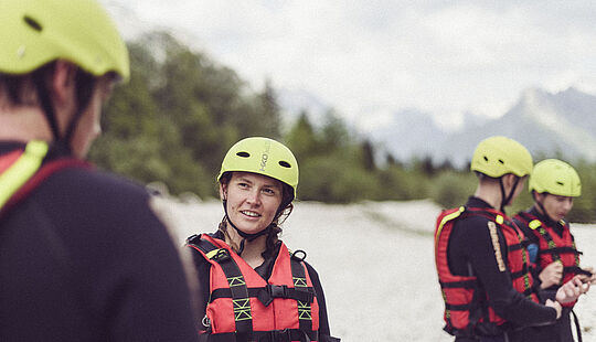 Nahaufnahme einer Person mit Helm und Schwimmweste vor Beginn der Raftingtour bei München